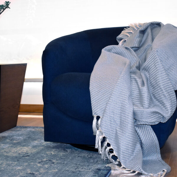 foto ambiente frazada Cavalari azul puesta sobre sofá azul en espacio minimalista. All Star muebles