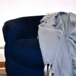 foto ambiente frazada Cavalari azul puesta sobre sofá azul en espacio minimalista. All Star muebles