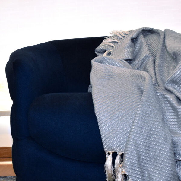 foto ambiente frazada Cavalari azul puesta sobre sofá azul en espacio minimalista. All Star muebles