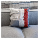 Funda con cojín cuadrado Antología multicolor con tejido artesanal decorativo, ubicada sobre sofá gris en ambiente minimalista, foto plano americano. All Star muebles