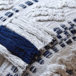 detalle funda con cojín Antología 45 con textura detalles tejidos artesanales decorativos, en tela blanca y azul primer plano. All Star decoración