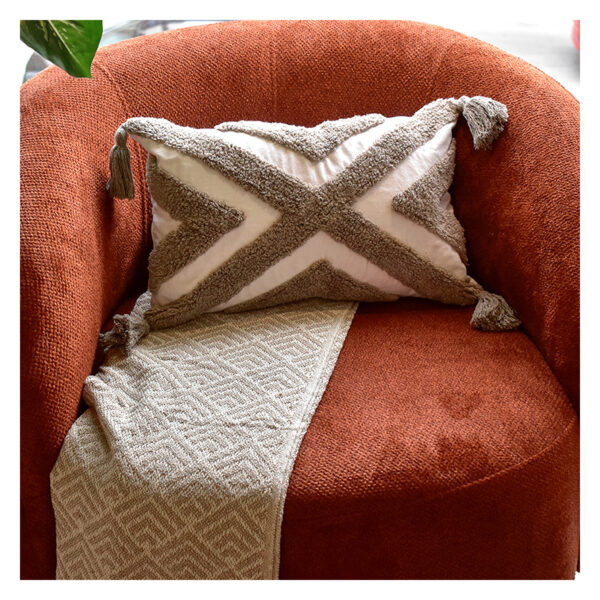 Funda con cojín rectangular Rustic color blanco con detalles moka y textura afelpada, ubicada sobre sofá rojo con una manta blanca complementaria, foto plano americano. All Star muebles