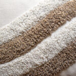 Detalle textura funda rectangular con cojín rustic 50 color blanco con detalles en avellana, textura afelpada y lisa. All Star decoración