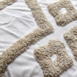 Detalle textura funda con cojín rustic 45 color blanco con detalles beige, textura afelpada y lisa. All Star decoración