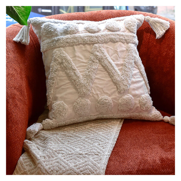 Funda con cojín Rustic color blanco con textura afelpada, ubicada sobre sofá rojo con una manta blanca complementaria, foto plano americano. All Star muebles