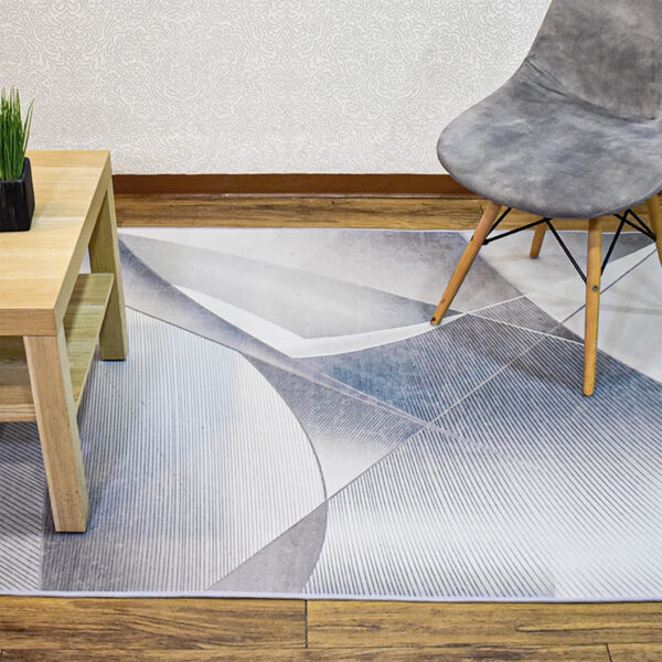 Ambiente de sala minimalista moderno con mesa auxiliar en madera, silla tapizada gris con patas en madera y tapete plateado y azul con textura geométrica. All Star decoración