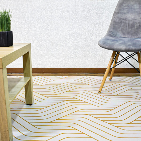 Ambiente de sala minimalista moderno con mesa auxiliar en madera, silla tapizada gris con patas en madera y tapete gris con textura geométrica dorada. All Star decoración