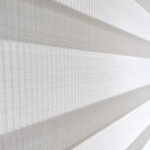 Detalle de persiana enrollable tipo zebra en tono blanca con textura de tela y acabado brillante. All Star decoración