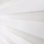 Detalle de persiana enrollable tipo zebra en tono blanca con textura de tela. All Star decoración