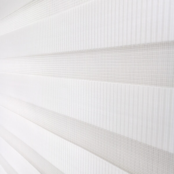 Detalle de persiana enrollable tipo zebra en tono blanca con textura de tela. All Star decoración