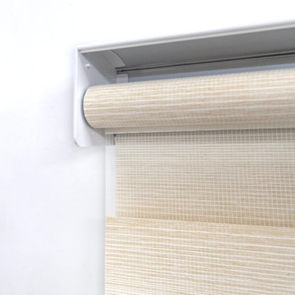 Detalle del mecanismo de una persiana enrollable tipo zebra con cadena plástica blanca y soporte lateral, textura enlazada vertical. All Star decoración