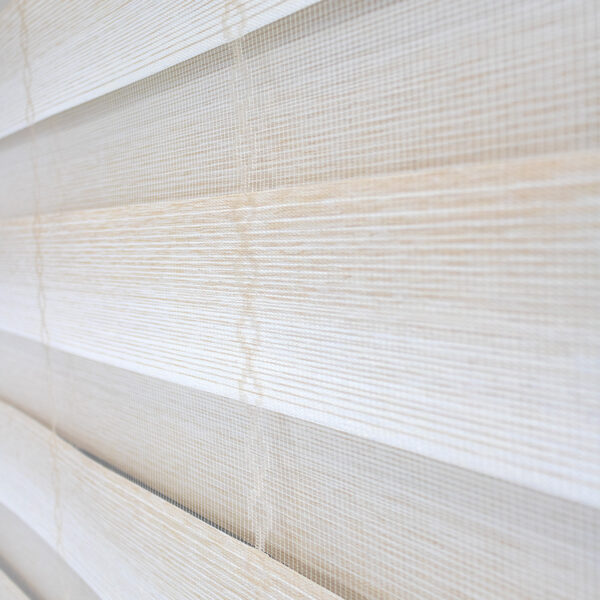 Detalle de persiana enrollable tipo zebra en tono ivory con textura de tela de enlazada vertical. All Star decoración