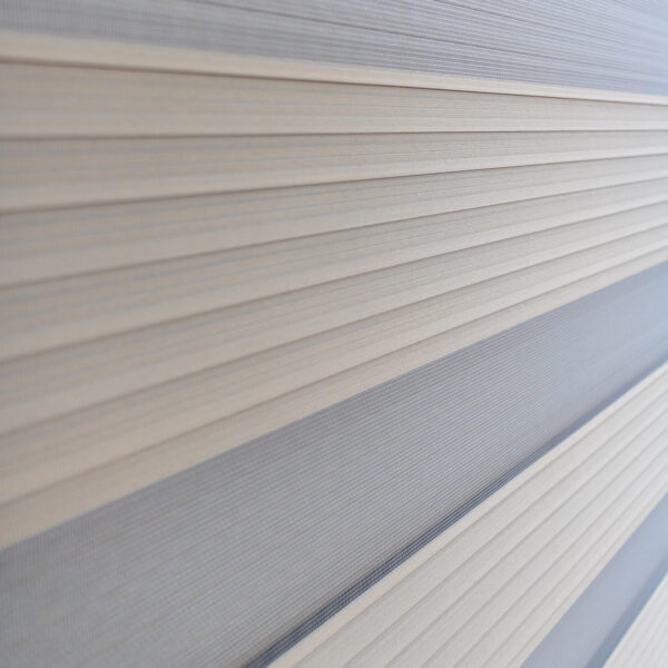 Detalle de persiana enrollable tipo zebra en tonos beige con textura de tela horizontal. All Star decoración