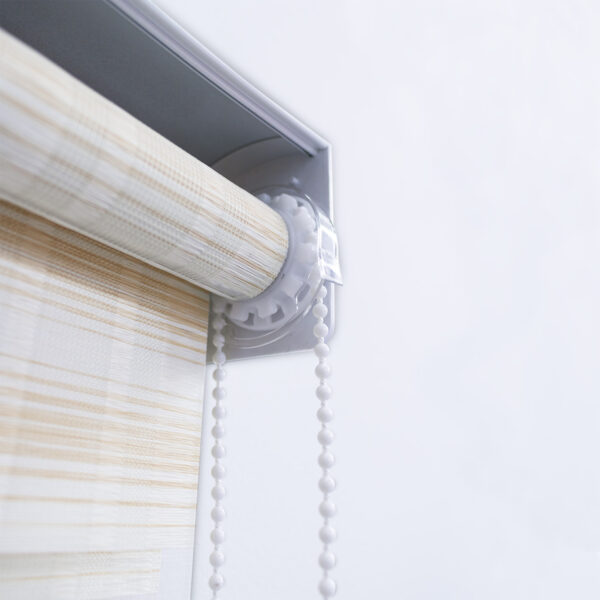 Detalle del mecanismo de una persiana enrollable tipo zebra con cadena plástica blanca y soporte lateral. All Star decoración