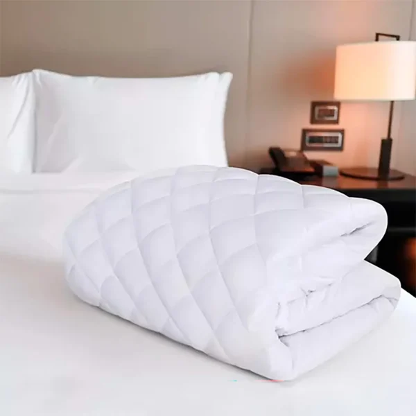 protector de colchón blanco acolchado doblado sobre cama con tendidos, en ambiente minimalista moderno. Muebles All Star