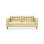Sofá Honey 3 puestos tapizado en color beige con capitoneado, patas en madera maciza tono envejecido al 50% torneadas, visto desde frente.