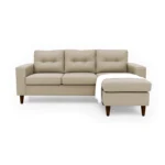 Sala en L Cielo con puff intercambiable tapizada en color avellana, capitoneado en espaldar, con manta decorativa color blanca y patas en madera tono envejecido 100% torneadas vista de frente. Muebles All Star